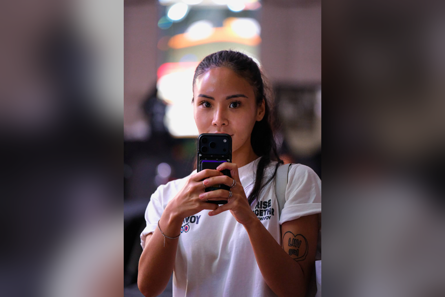 A woman in a Konvoy shirt holds a smartphone at Konvoy 03.