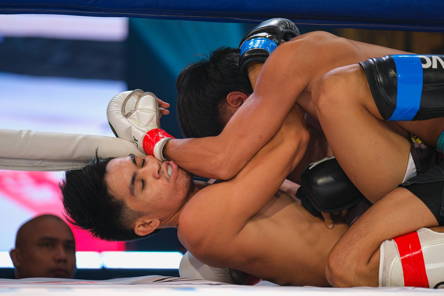 A fighter traps an opponent’s upper body with his legs in the ring at KONVOY 03.