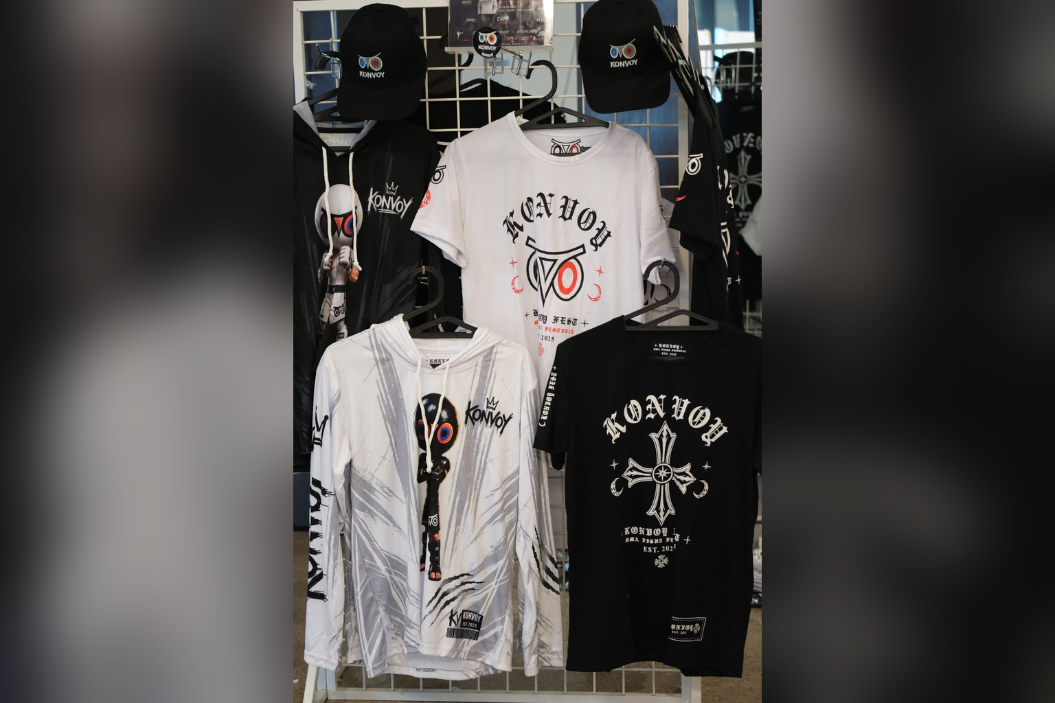 Konvoy shirts, hoodies and caps hang on a merchandise display.